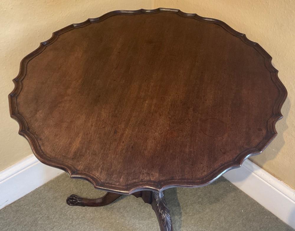 A nineteenth-century mahogany tripod table featuring a scalloped piecrust top, a fluted column, and carved cabriole legs terminating in claw feet. View II