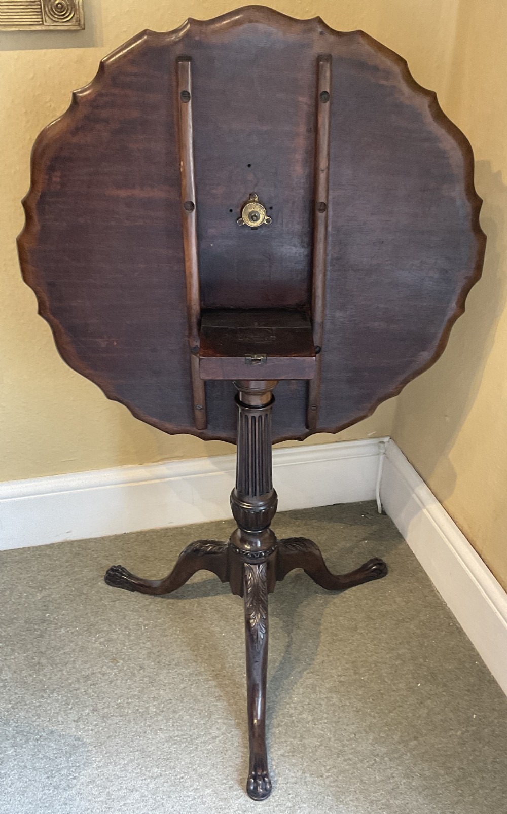 A nineteenth-century mahogany tripod table featuring a scalloped piecrust top, a fluted column, and carved cabriole legs terminating in claw feet. View IX