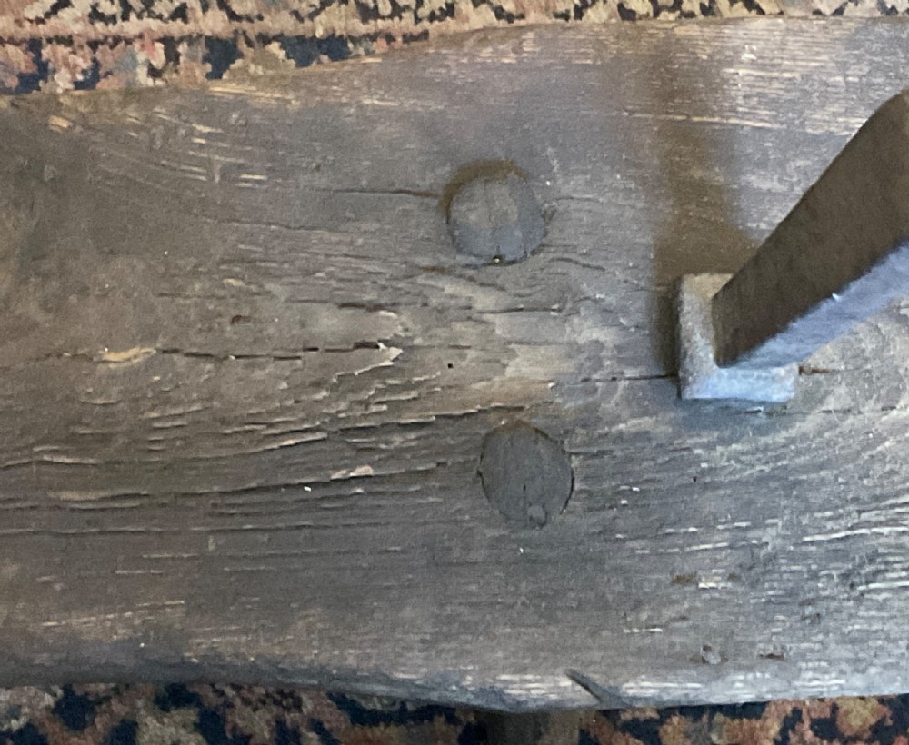 A rustic dark oak cobbler bench featuring a thick timber top with integrated iron tools and sturdy wooden leg supports. View IX