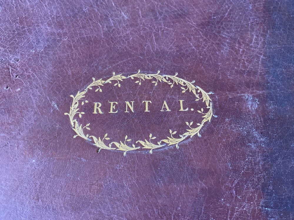 An 18th-century dark brown leather-bound ledger featuring a central gilt oval wreath cartouche with the word RENTAL stamped in gold. View XI