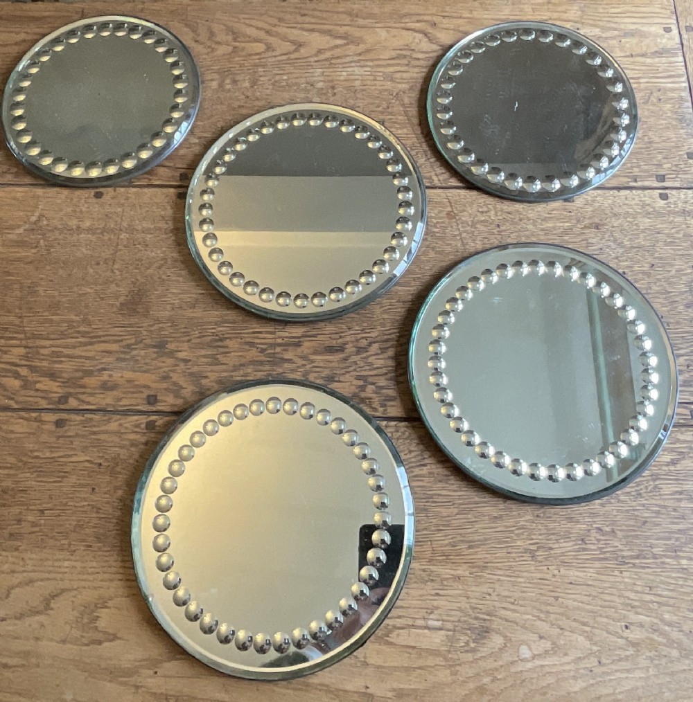 A collection of five circular convex sorcerer mirrors featuring beaded glass border detailing.