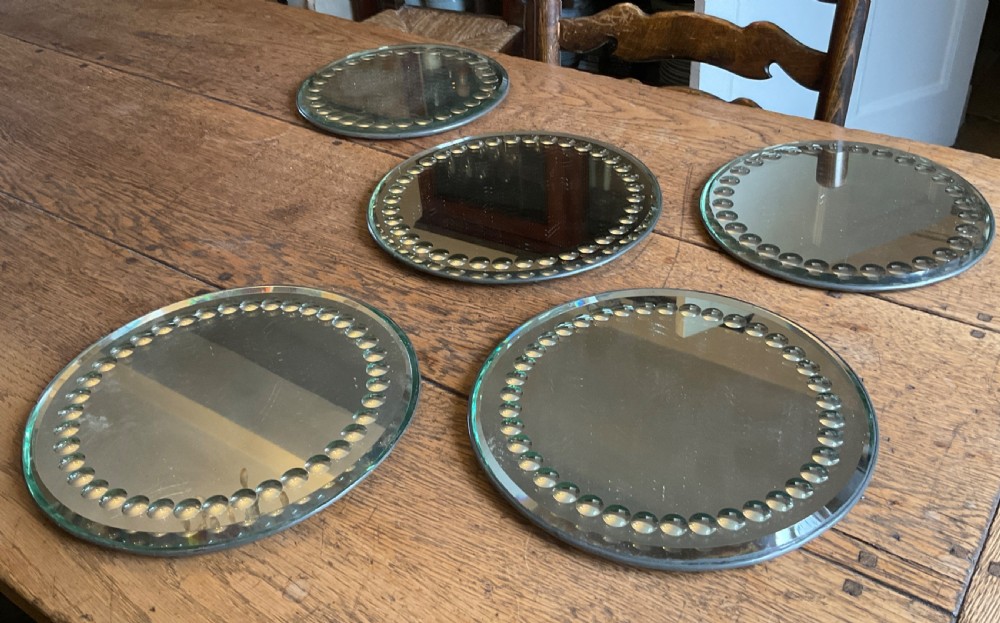 A collection of five circular convex sorcerer mirrors featuring beaded glass border detailing. View IX