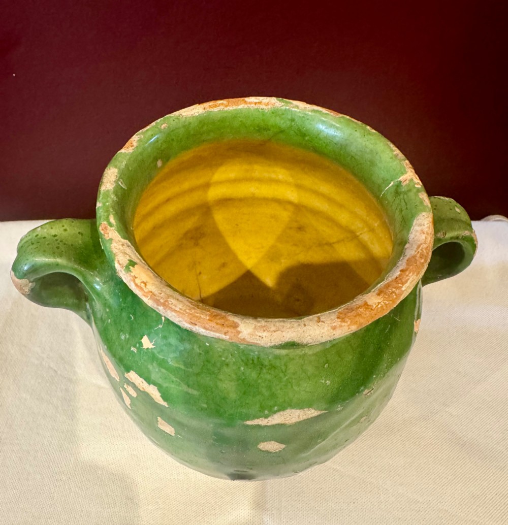 An antique French terracotta confit pot featuring a green glaze on the upper body, two loop handles, and an unglazed earthen base. View III