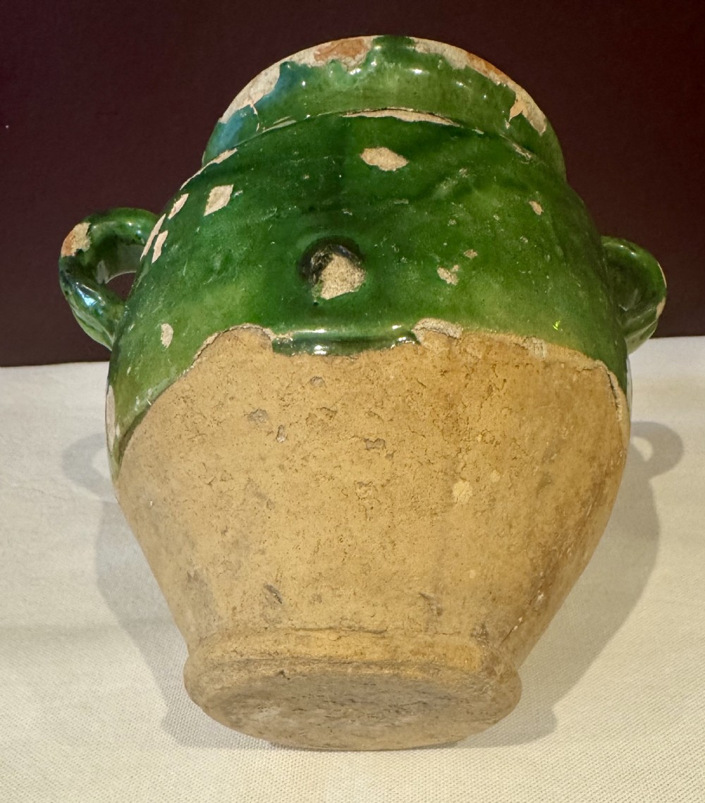 An antique French terracotta confit pot featuring a green glaze on the upper body, two loop handles, and an unglazed earthen base. View IV