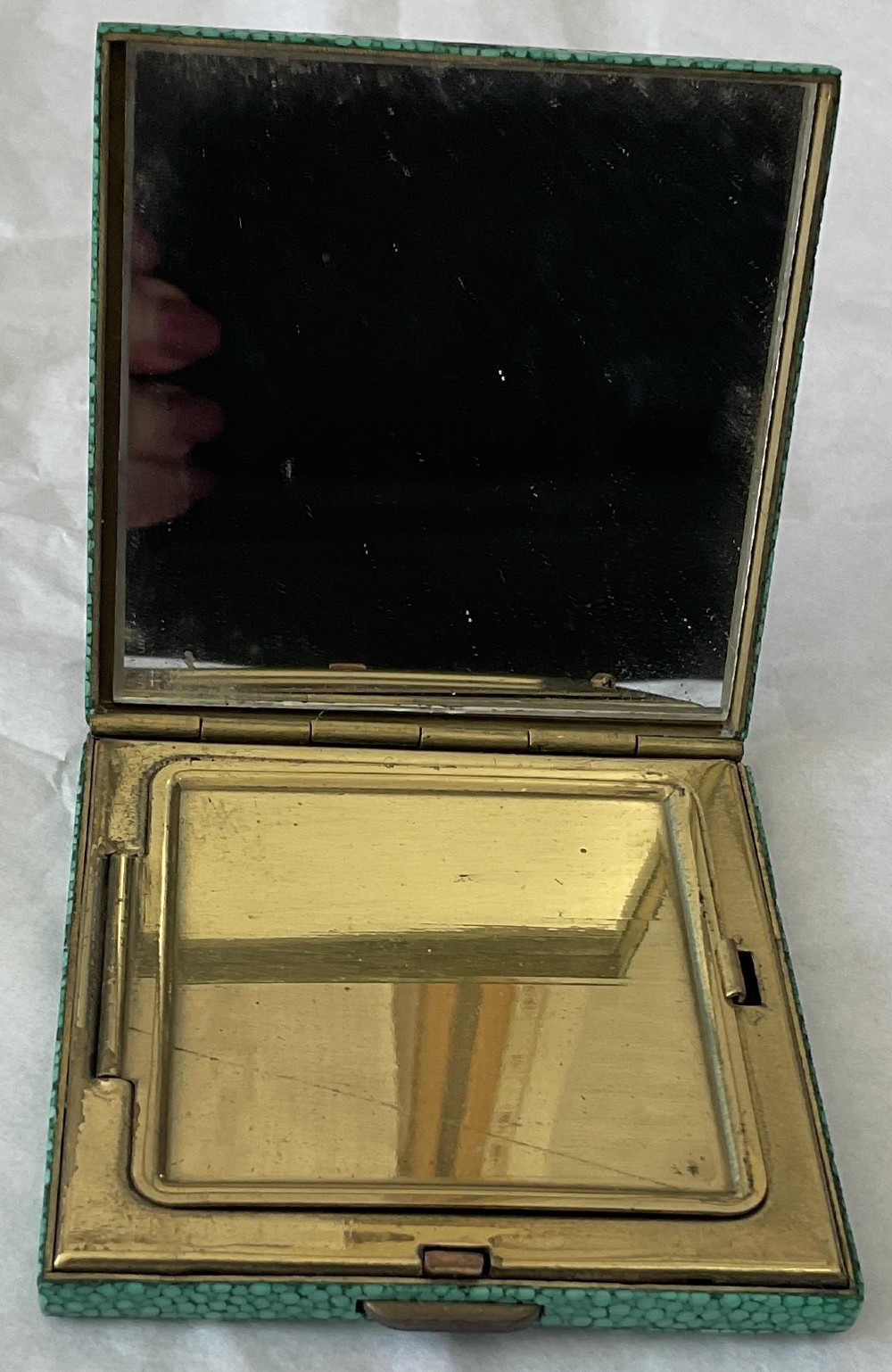 A square Art Deco vanity compact covered in green dyed shagreen with a brass catch. View II