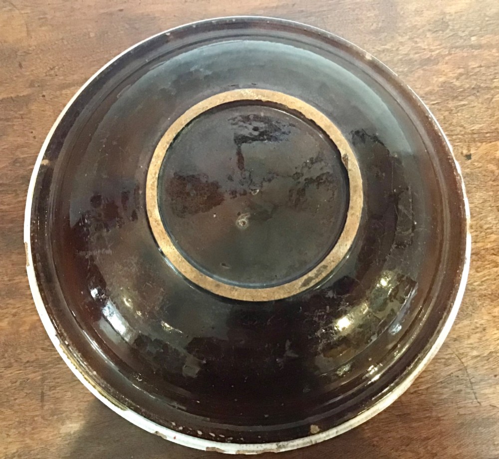 An antique round French tin-glazed earthenware bowl featuring a cream-coloured interior with blue circular lines and a central floral motif. View III