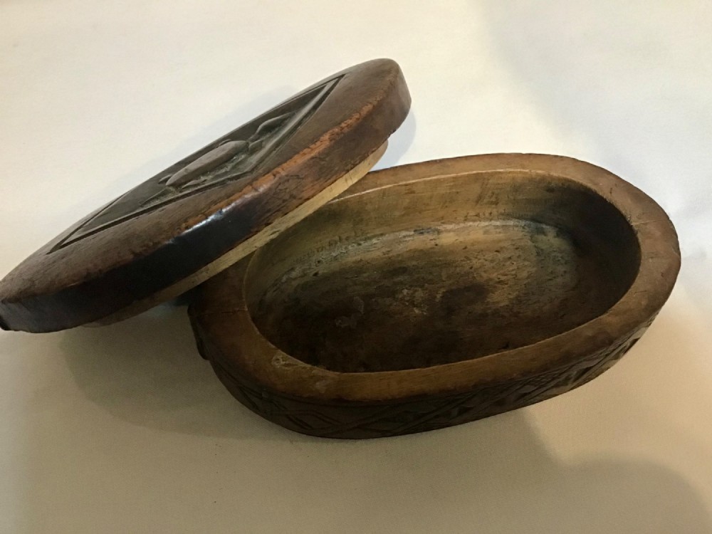 An oval hand-carved dark wood box featuring geometric relief patterns on the lid and sides. View IV