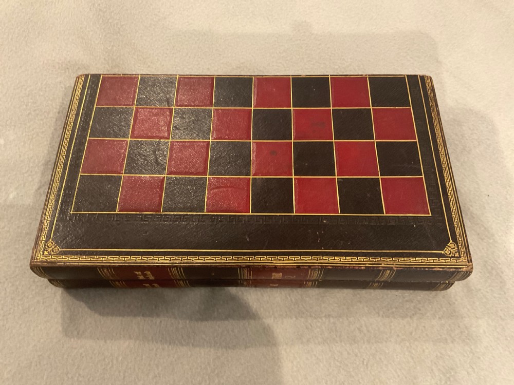An open dark brown leather games board disguised as a book, displaying red and green backgammon points with black and cream counters. View II