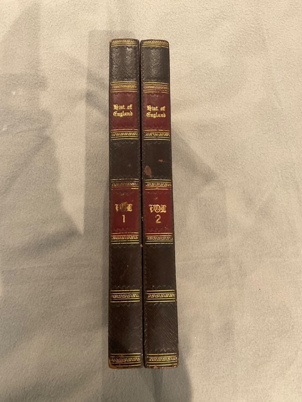 An open dark brown leather games board disguised as a book, displaying red and green backgammon points with black and cream counters. View IV