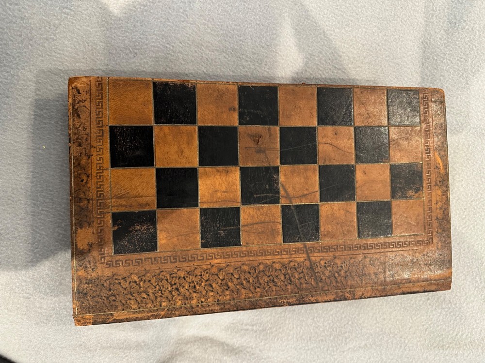 An antique closed leather-bound faux book games board decorated with a black and tan chequerboard pattern and gilt-tooled borders. View III
