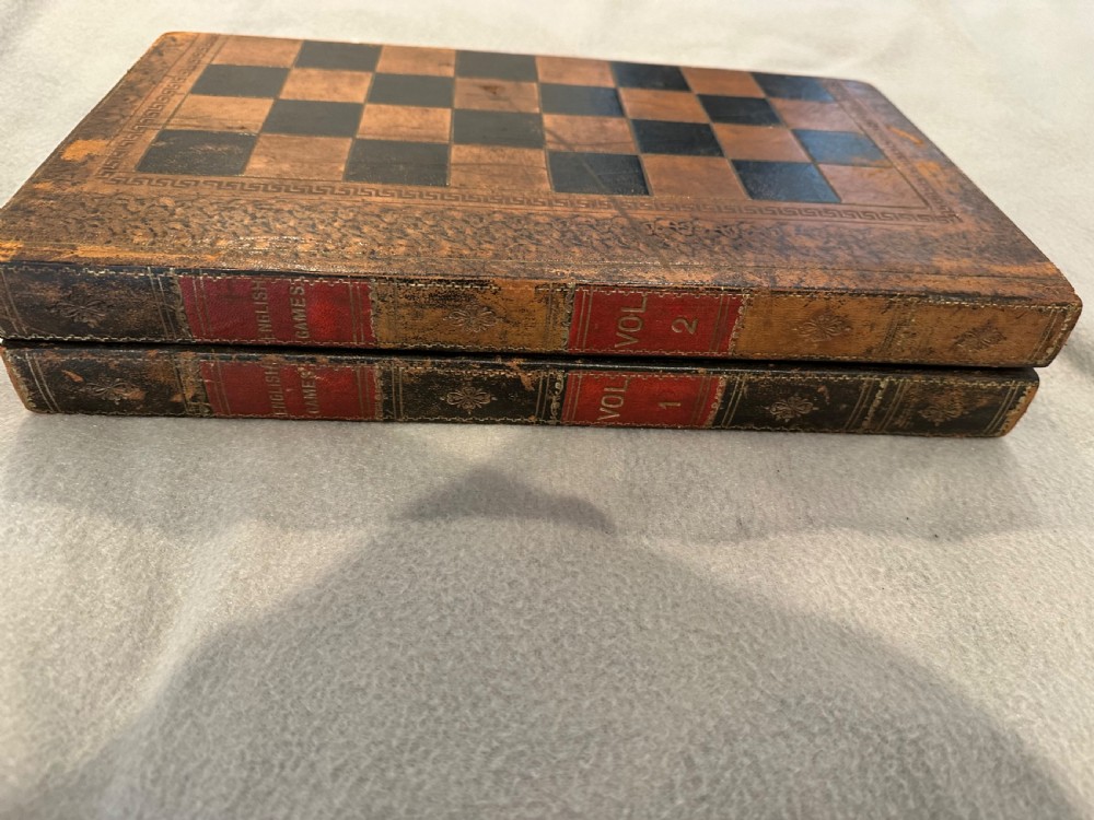 An antique closed leather-bound faux book games board decorated with a black and tan chequerboard pattern and gilt-tooled borders. View IV
