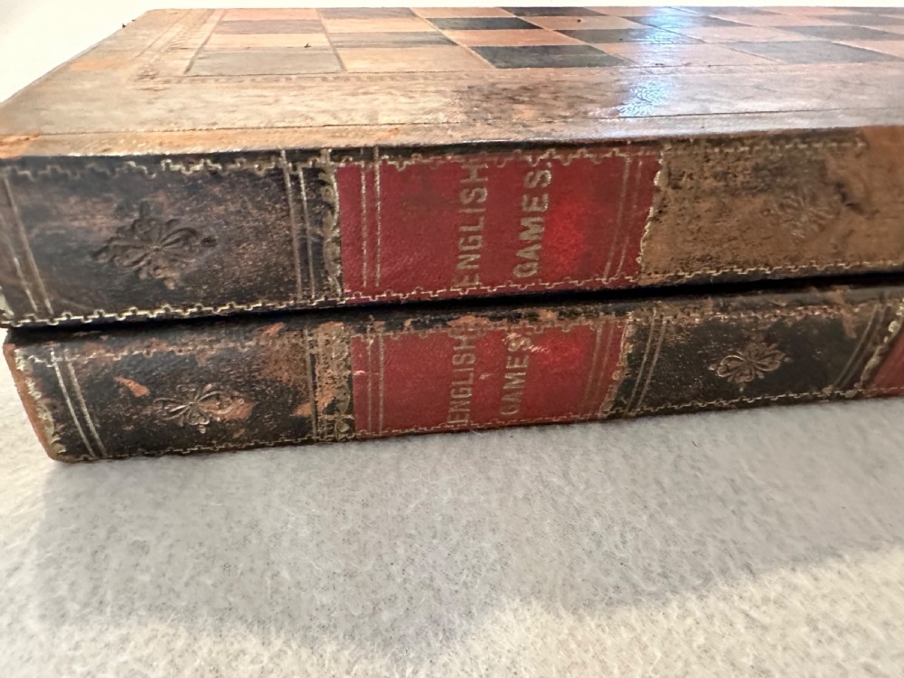 An antique closed leather-bound faux book games board decorated with a black and tan chequerboard pattern and gilt-tooled borders. View V