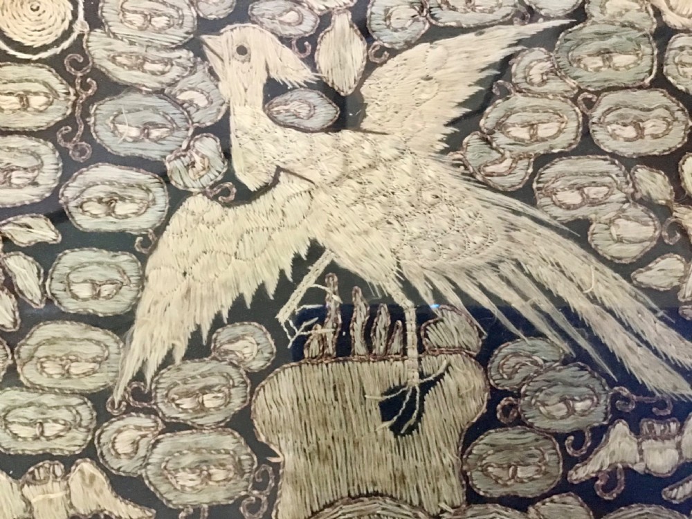 A square framed Chinese silk rank badge featuring a central embroidered bird surrounded by clouds, bats, and water waves in cream silk thread against a dark background. View II