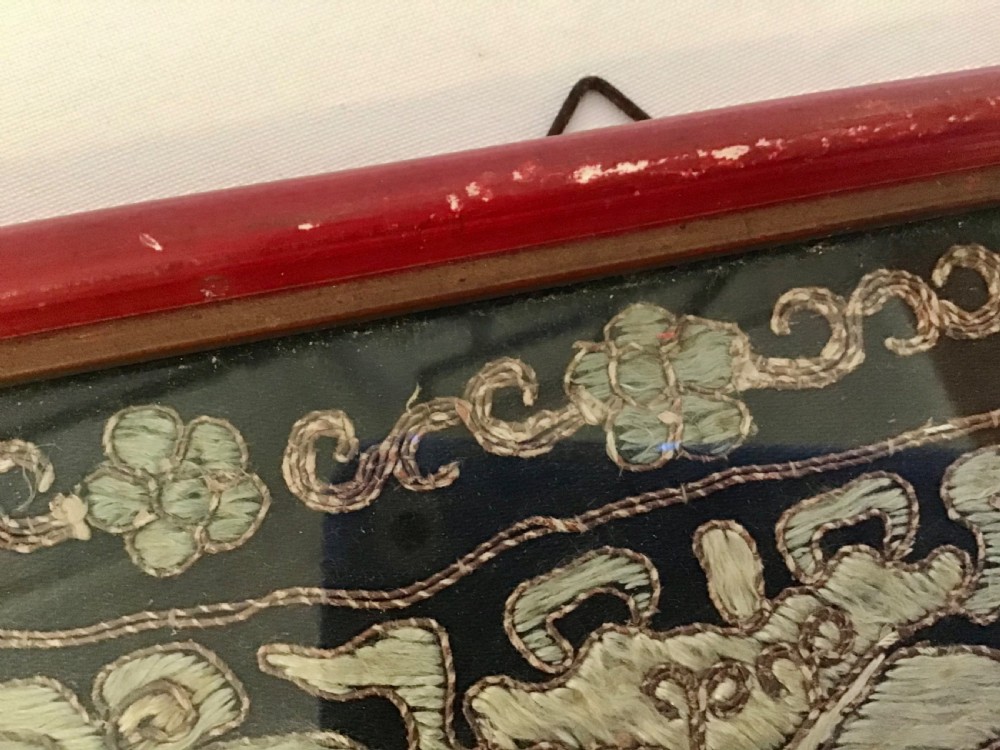 A square framed Chinese silk rank badge featuring a central embroidered bird surrounded by clouds, bats, and water waves in cream silk thread against a dark background. View III
