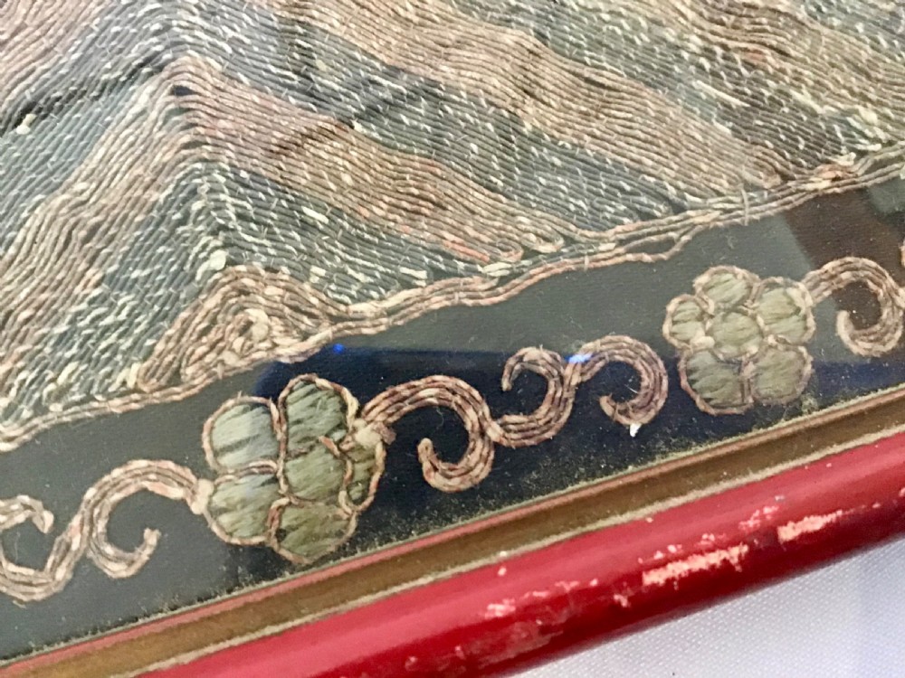 A square framed Chinese silk rank badge featuring a central embroidered bird surrounded by clouds, bats, and water waves in cream silk thread against a dark background. View V