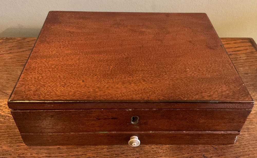 An open Georgian mahogany artist paintbox displaying original pigment cakes, a porcelain palette, a decorated ceramic dish, and a printed maker label inside the lid. View VI
