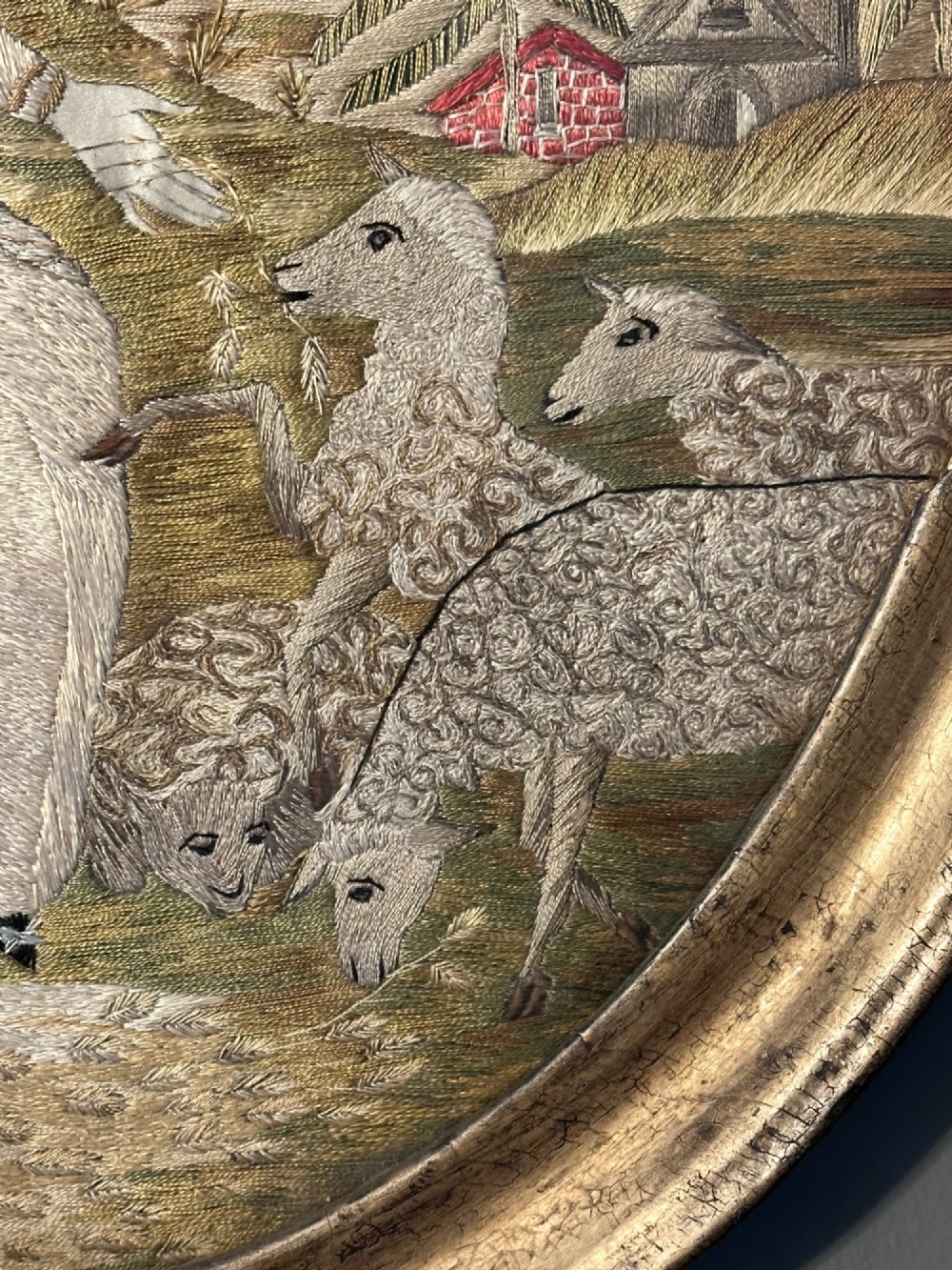 An oval Regency embroidered silk picture depicting a shepherdess and sheep under a tree within a gilded frame. View III