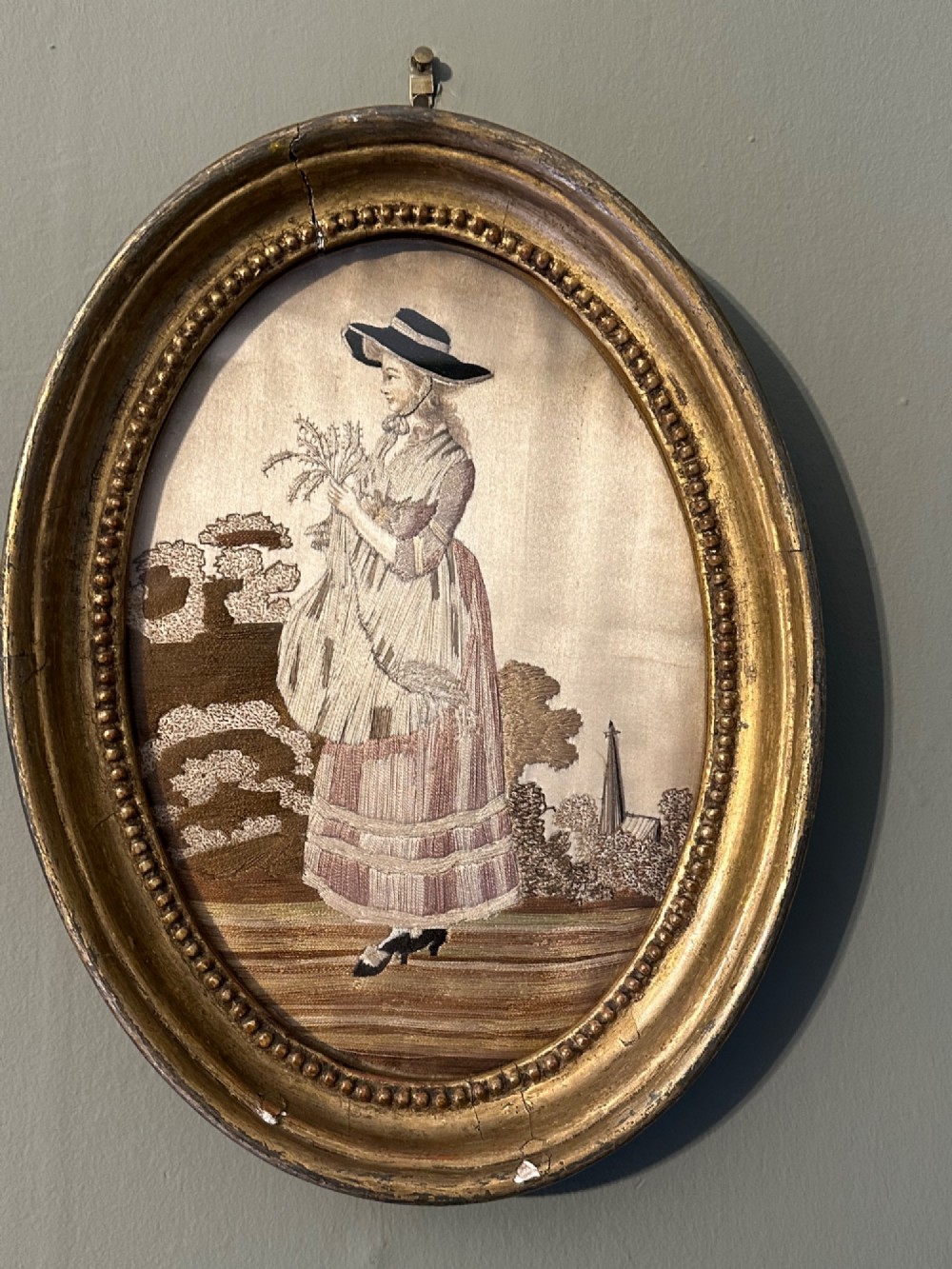 An oval Regency embroidered silk picture depicting a shepherdess and sheep under a tree within a gilded frame. View VIII