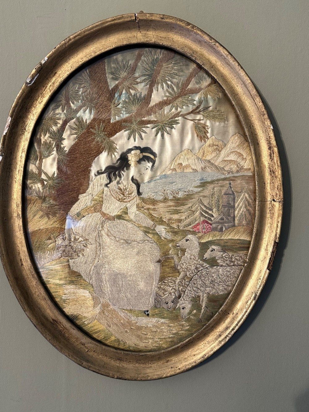 An oval Regency embroidered silk picture depicting a shepherdess and sheep under a tree within a gilded frame. View IX