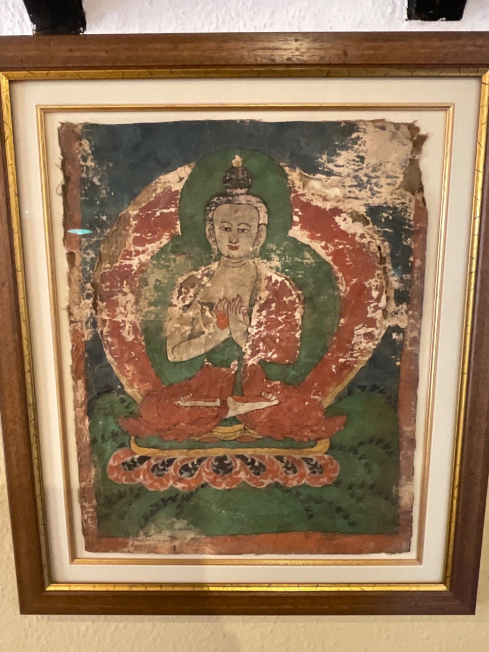 Framed 17th-century Tibetan canvas painting depicting the seated Vairocana Buddha with a red and green halo. View V