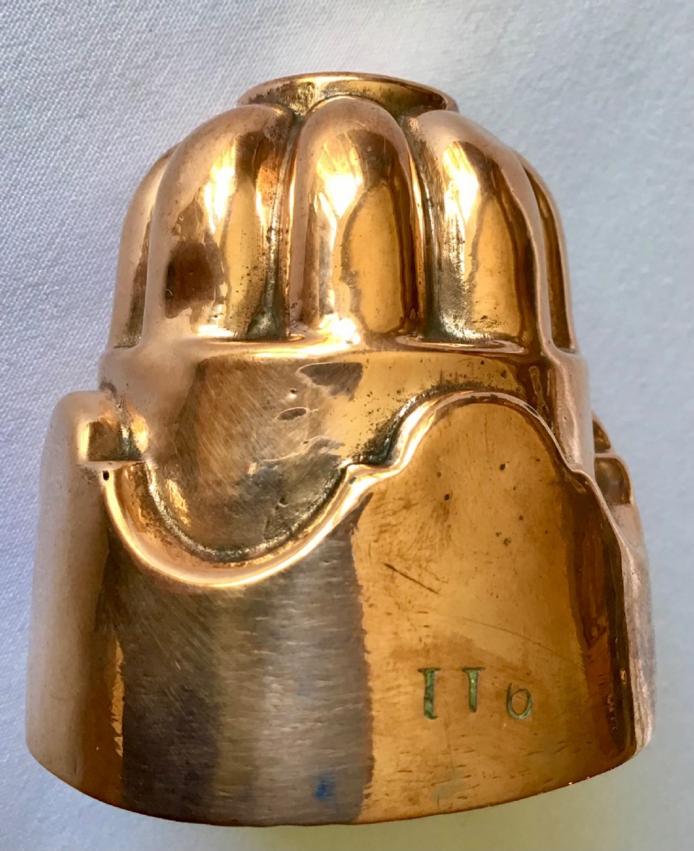 A small polished copper jelly mould featuring a two-tiered design with fluted vertical lobes on the upper section and a scalloped base. View II