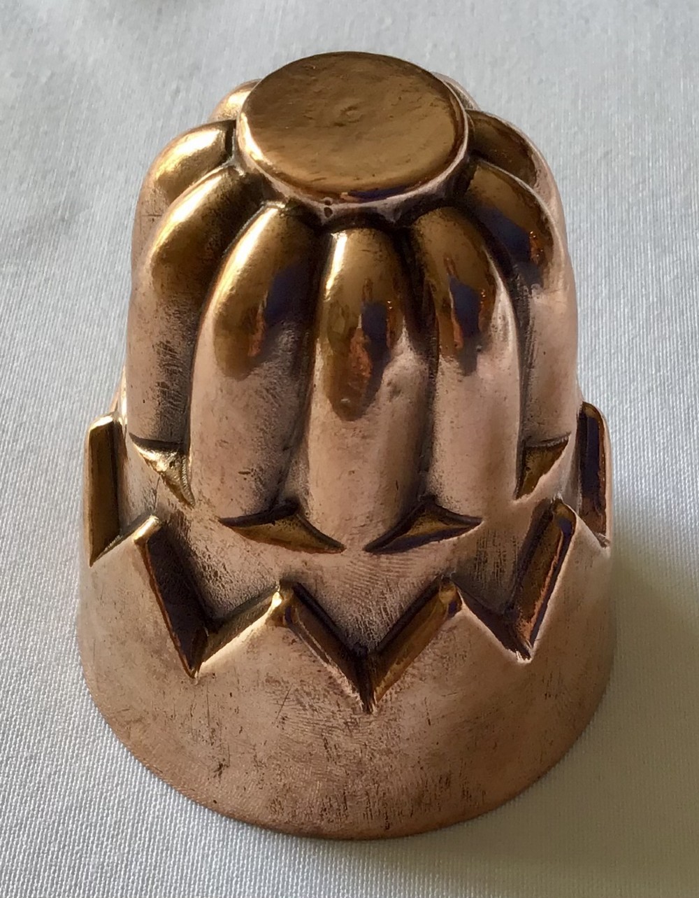 A miniature Victorian copper jelly mould featuring a lobed top section and a castellated geometric lower rim design with a warm patina.