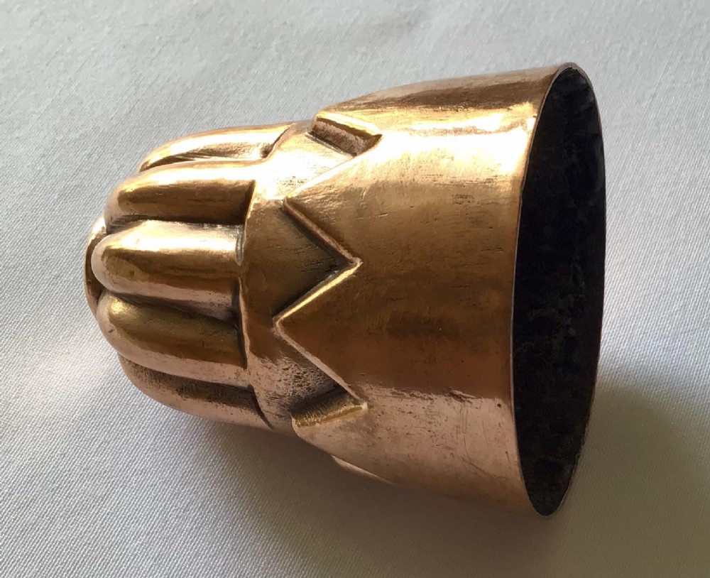 A miniature Victorian copper jelly mould featuring a lobed top section and a castellated geometric lower rim design with a warm patina. View II