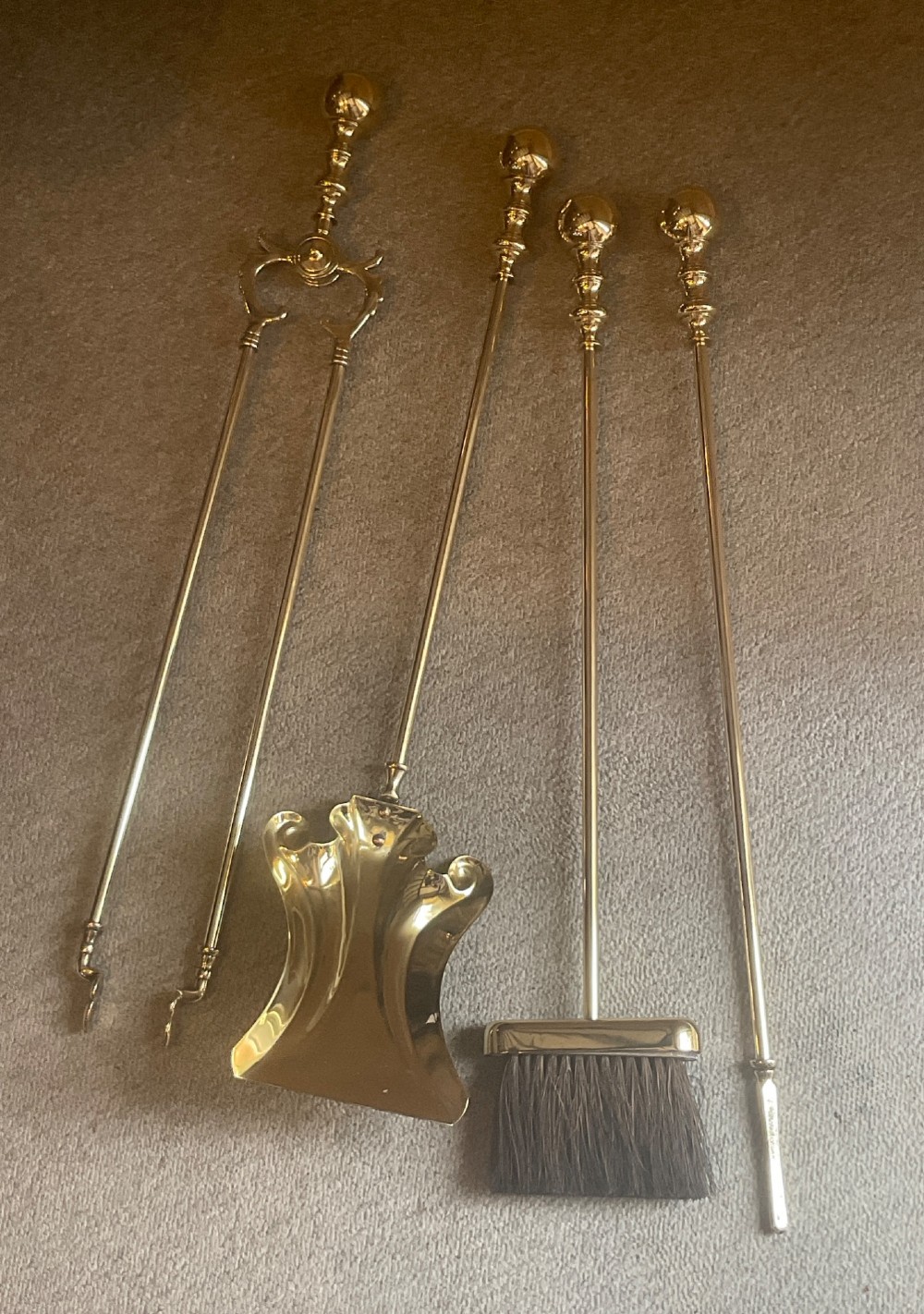 A polished brass companion set featuring a central stand with sphere finials holding a shovel, tongs, poker, and hearth brush. View IV