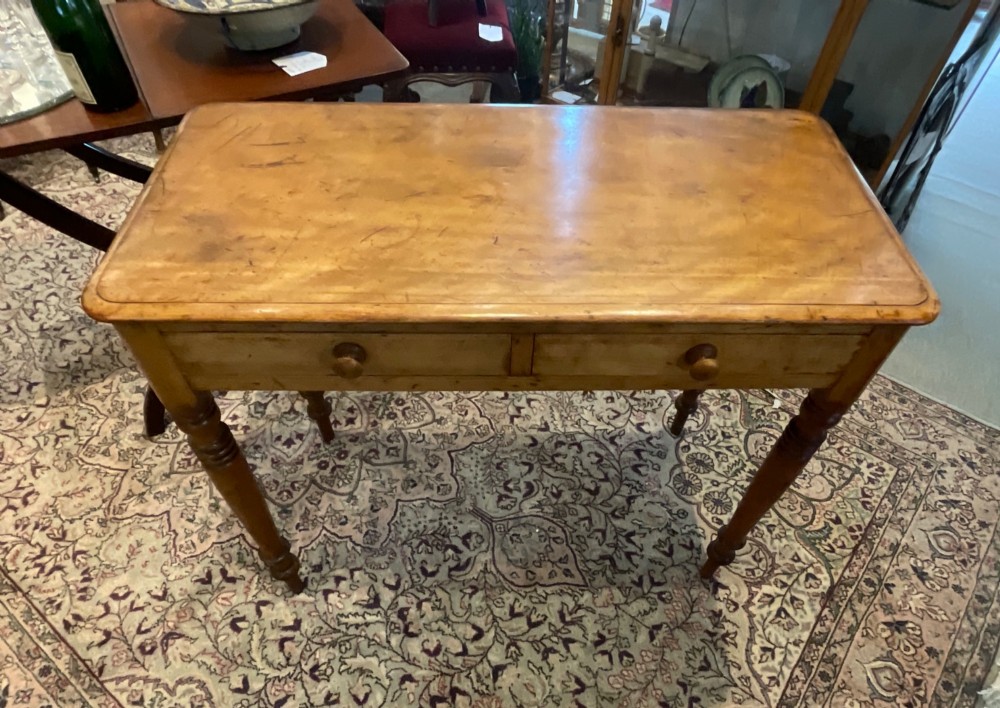 A Victorian satin walnut side table featuring two frieze drawers with wooden knob handles and four turned legs. View VI