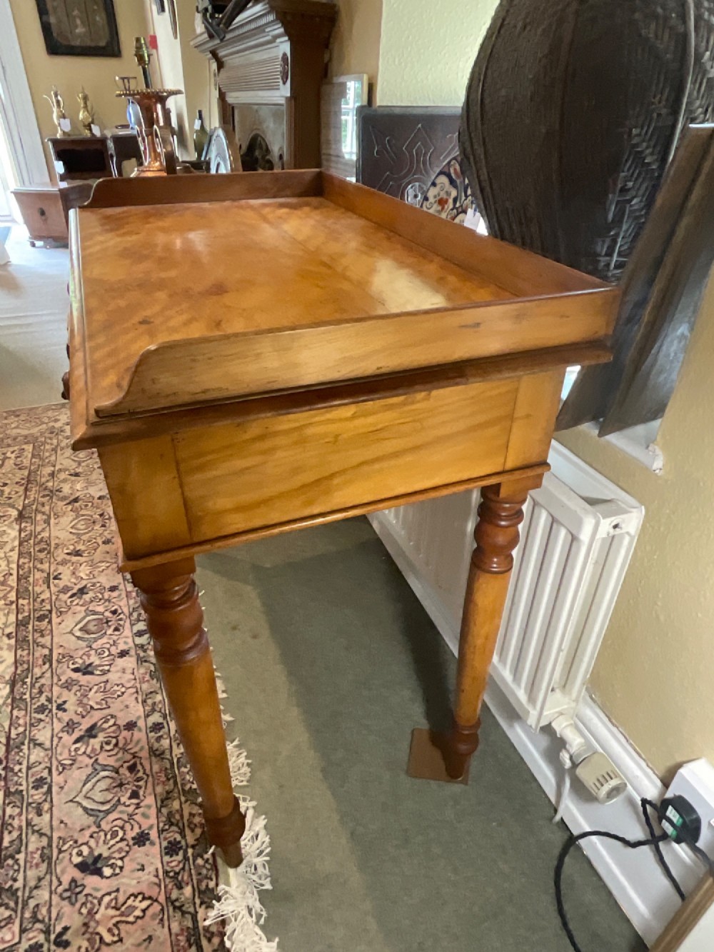 A Victorian satin birch writing desk featuring a three-quarter gallery top, two frieze drawers with turned wooden knobs, and four turned legs. View VI