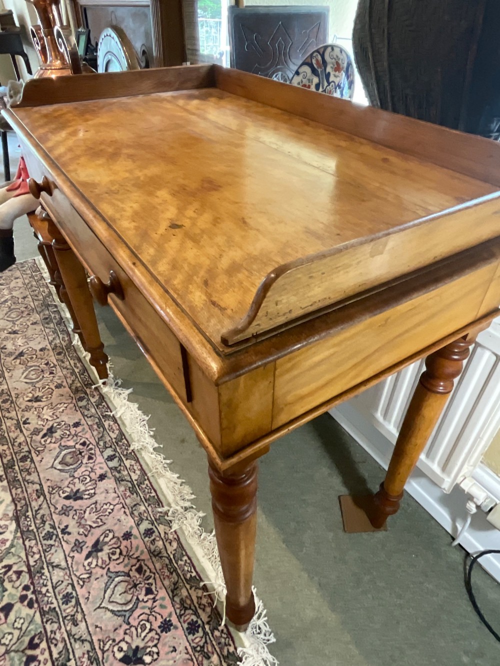 A Victorian satin birch writing desk featuring a three-quarter gallery top, two frieze drawers with turned wooden knobs, and four turned legs. View VII