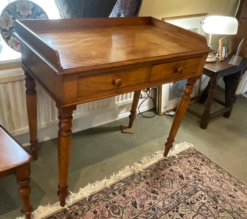 A Victorian satin birch writing desk featuring a three-quarter gallery top, two frieze drawers with turned wooden knobs, and four turned legs. View X