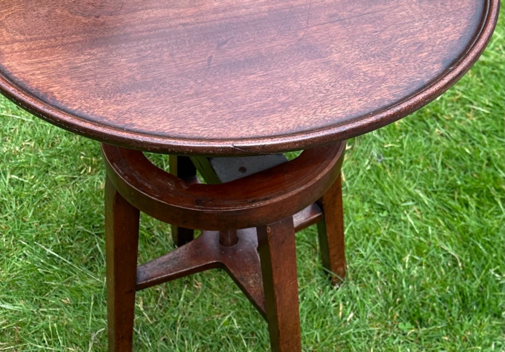 An antique round mahogany wine table with a moulded top and a threaded height-adjusting central screw resting on four legs. View VI