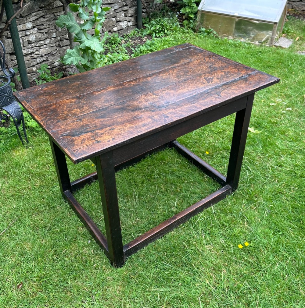 An antique dark brown oak table featuring a plank top surface, square legs, and low box stretchers. View II