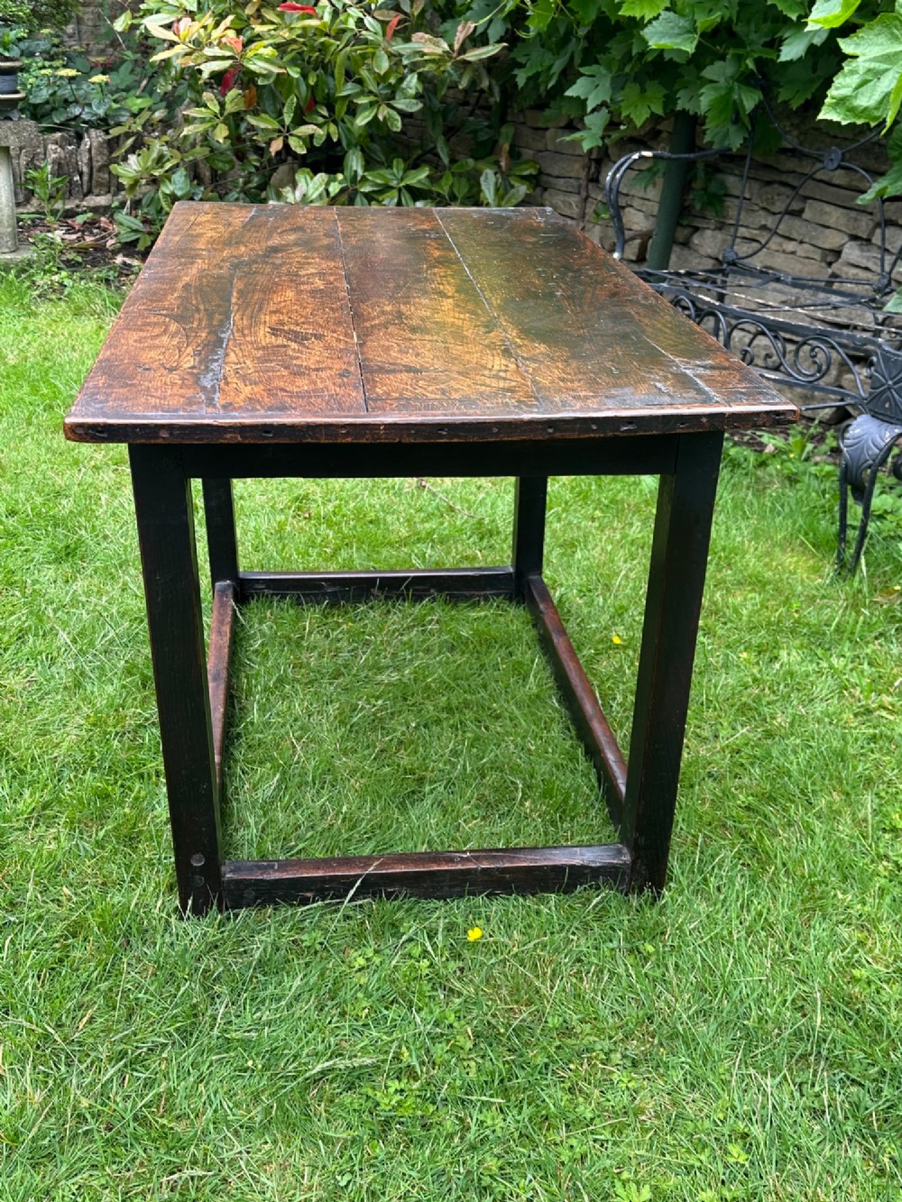 An antique dark brown oak table featuring a plank top surface, square legs, and low box stretchers. View III