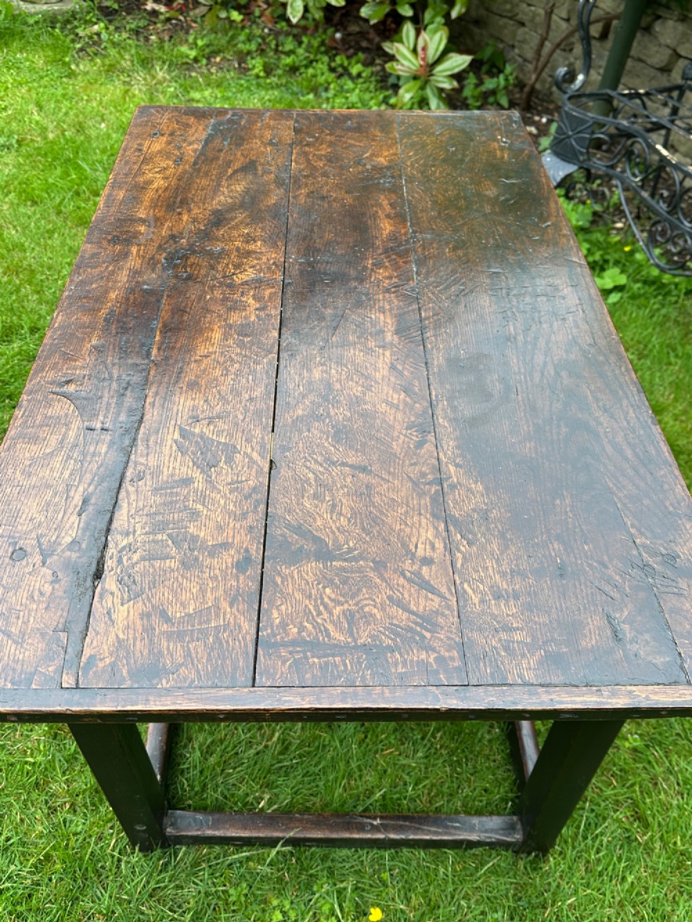 An antique dark brown oak table featuring a plank top surface, square legs, and low box stretchers. View V