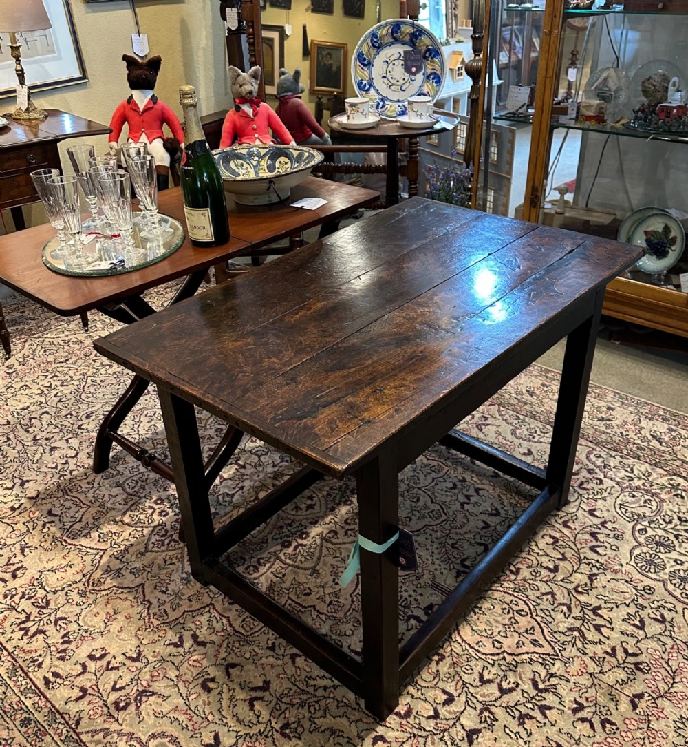 An antique dark brown oak table featuring a plank top surface, square legs, and low box stretchers. View VI
