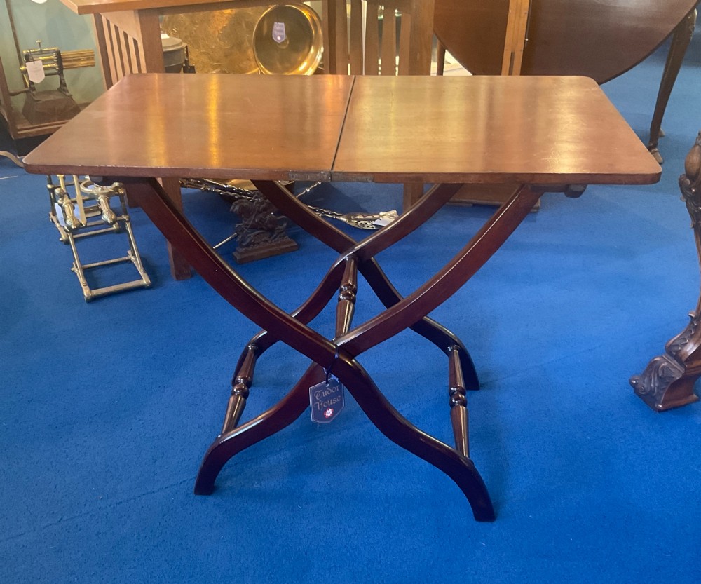 A Victorian mahogany coaching table featuring a hinged rectangular folding top supported by an X-frame base with turned stretchers.