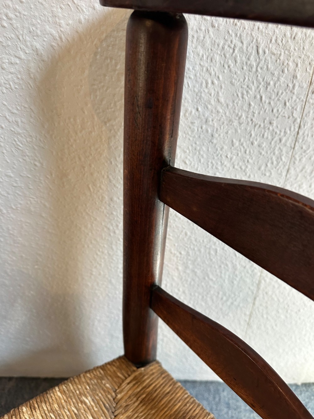 A pair of dark oak antique chapel chairs featuring woven rush seats, ladder back splats, and integrated top book ledges. View III
