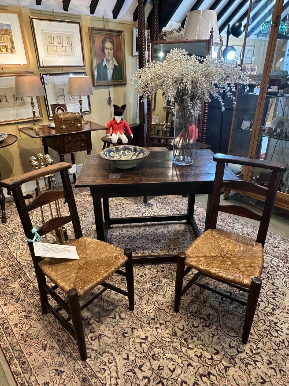 A pair of dark oak antique chapel chairs featuring woven rush seats, ladder back splats, and integrated top book ledges. View V