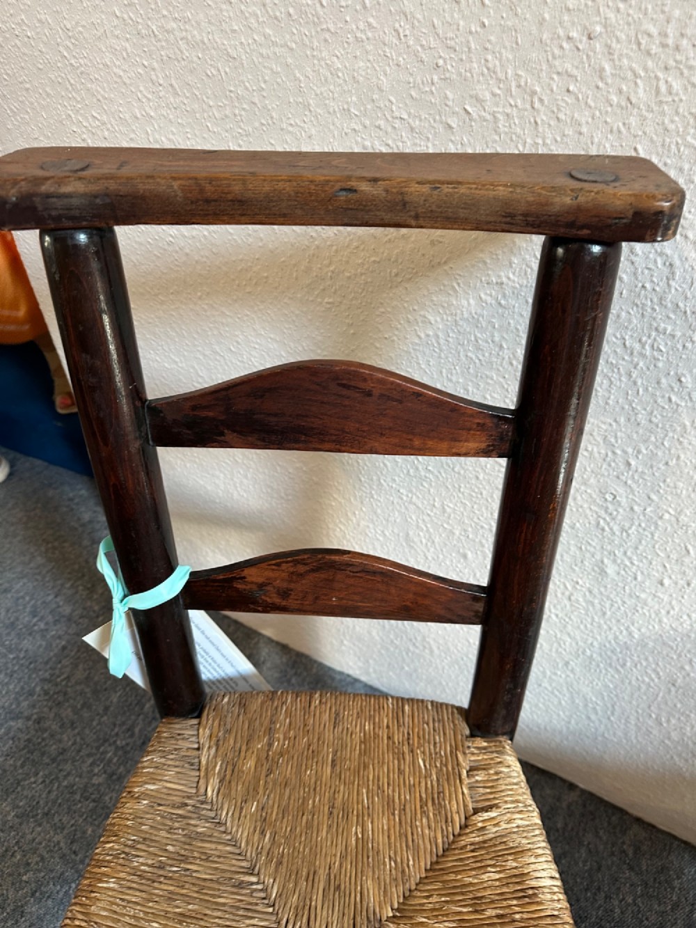 A pair of dark oak antique chapel chairs featuring woven rush seats, ladder back splats, and integrated top book ledges. View VI