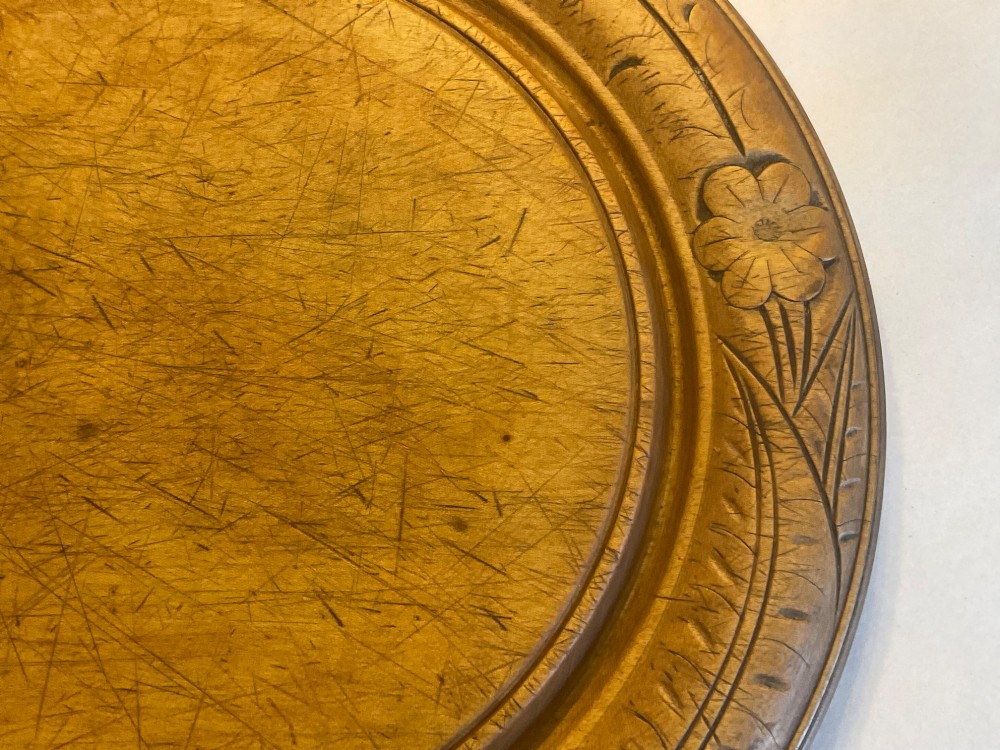 A circular antique carved wooden bread board featuring the word BREAD in relief alongside carved floral motifs around the border and knife marks in the centre. View III