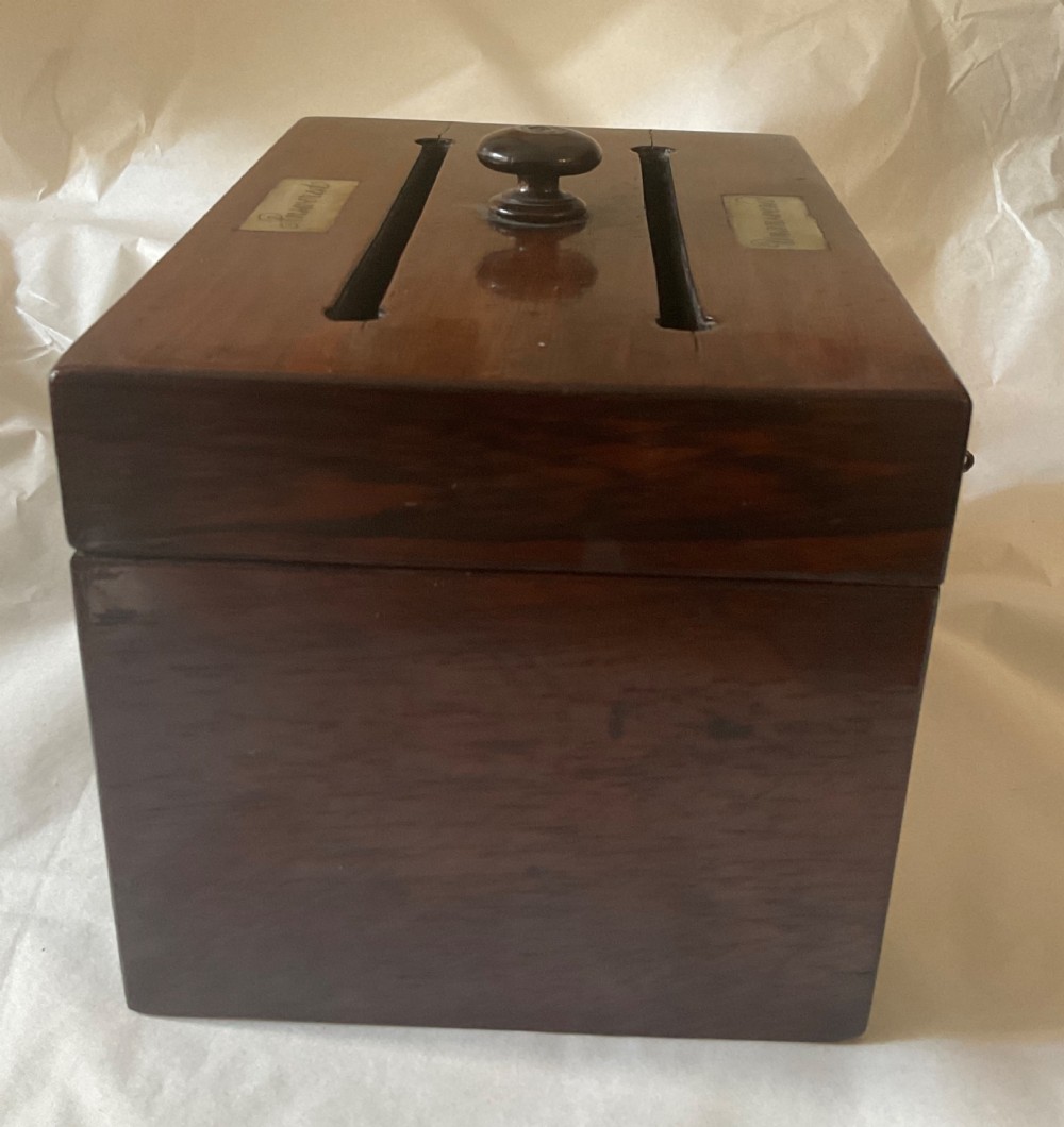 A dark mahogany 19th-century letter box featuring two top slots labelled Answered and Unanswered, a turned central knob, and a front keyhole with an inserted key. View VII
