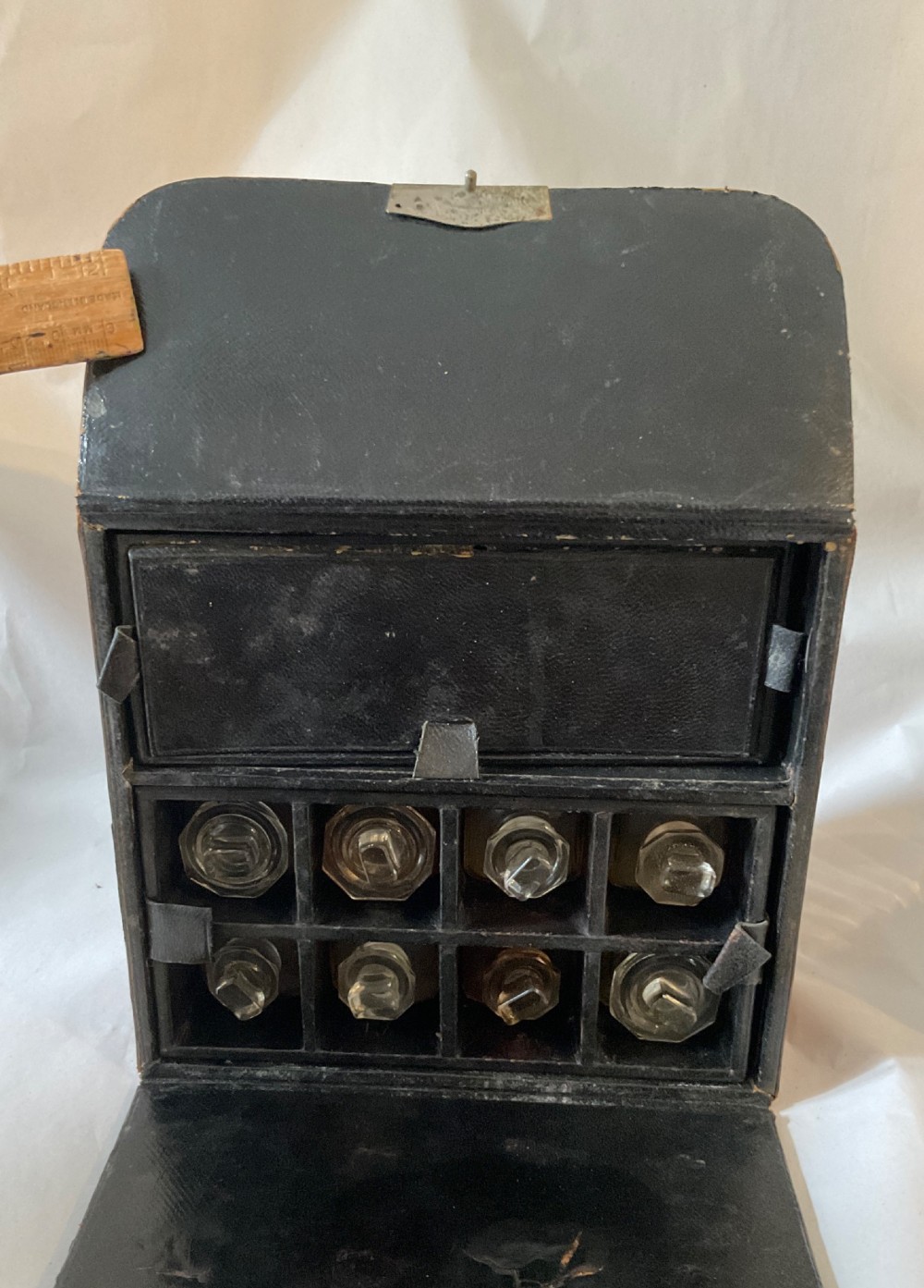 A square Victorian tan leather apothecary case featuring a fold-over front flap secured by a central metal latch. View II