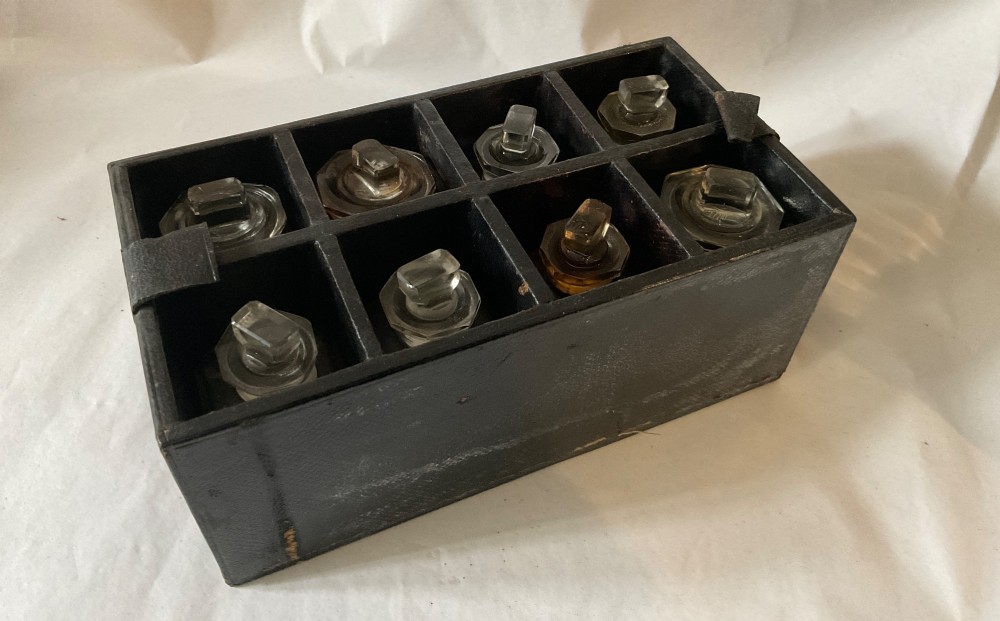 A square Victorian tan leather apothecary case featuring a fold-over front flap secured by a central metal latch. View V