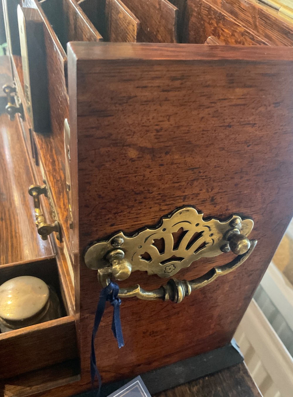 An open Victorian oak stationery box featuring internal tiered letter slots, two small drawers, a pen tray, a folding writing slope, and brass fittings. View VIII
