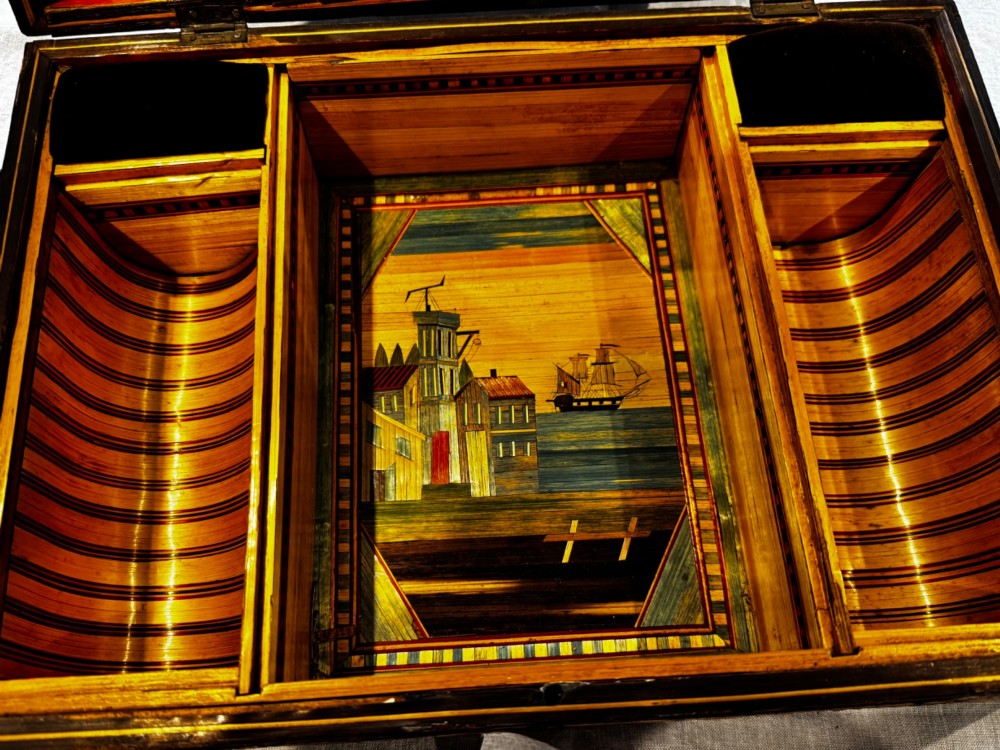 An antique rectangular wooden box embellished with straw marquetry forming a central floral basket surrounded by intricate decorative borders in golden yellow and brown shades. View VII