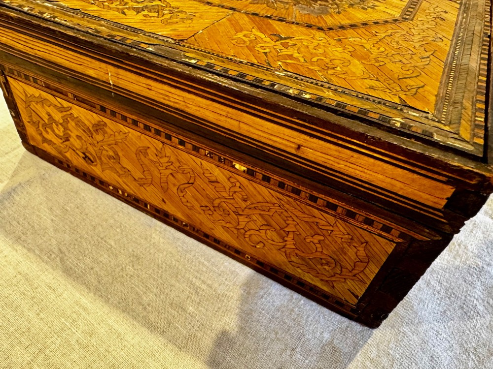 An antique rectangular wooden box embellished with straw marquetry forming a central floral basket surrounded by intricate decorative borders in golden yellow and brown shades. View XII