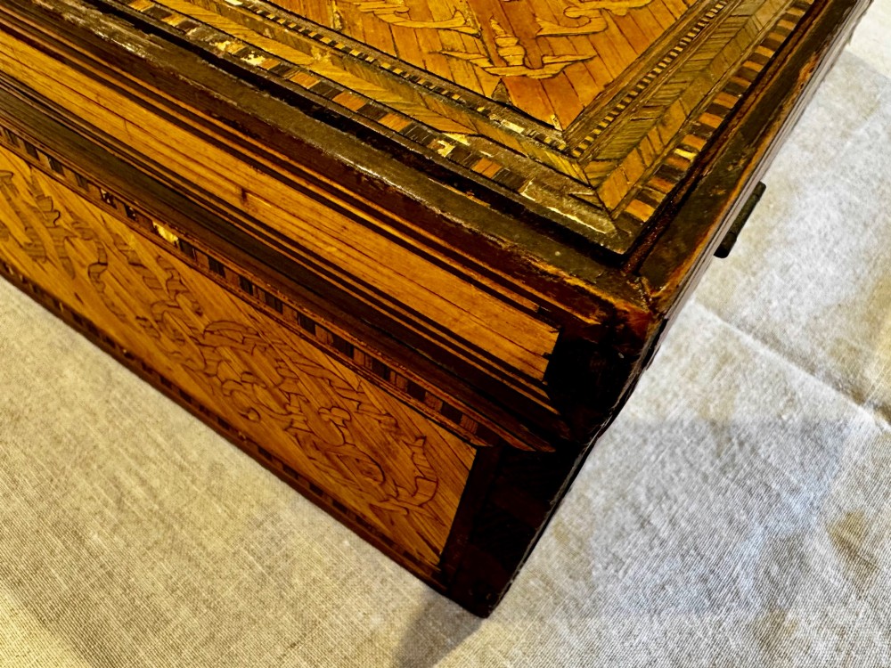 An antique rectangular wooden box embellished with straw marquetry forming a central floral basket surrounded by intricate decorative borders in golden yellow and brown shades. View XIII
