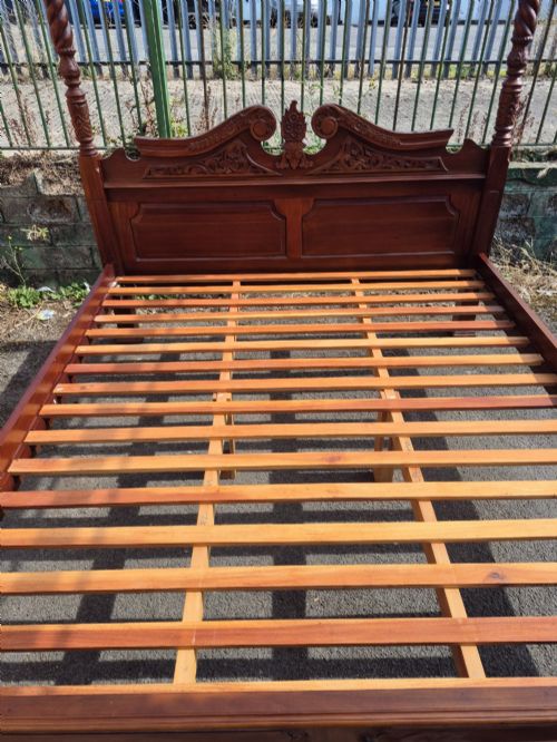 fig 2. A super king size four-poster bed frame crafted from dark carved wood featuring spiral twisted posts and a scrolled headboard crest.